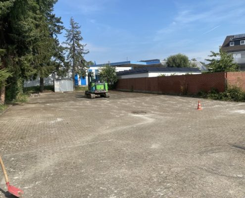 Ein leerer Parkplatz, auf dem ein kleiner Bagger steht.