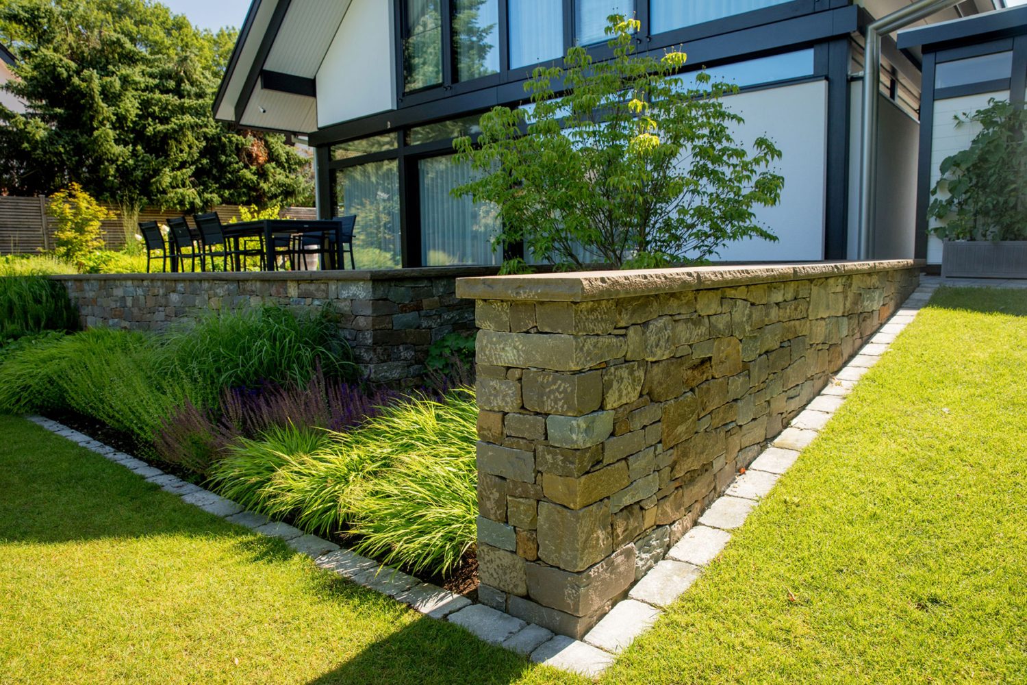 Gartenbeet mit Natursteinmauer und Rasenfläche