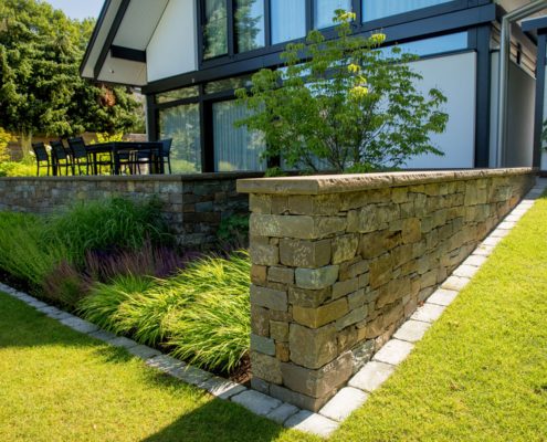 Gartenbeet mit Natursteinmauer und Rasenfläche