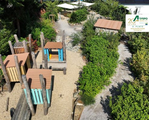 Kita-Außenanlage mit Staudenbepflanzung und kleinen Holzhäuschen Kita-Außenanlage mit Staudenbepflanzung und kleinen Holzhäuschen