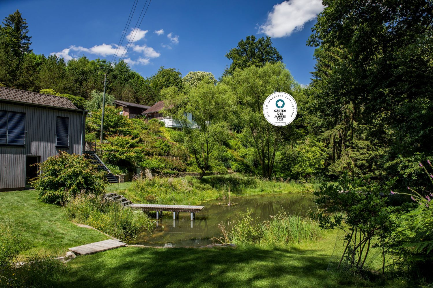 Dicht bewachsener Garten am Hang mit Steg zum Schwimmteich vor dem Wohnhaus